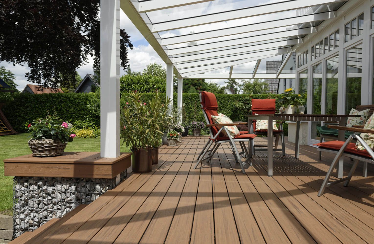 Gartenterrasse mit braunen Terrassendielen und Sitzmöbel.